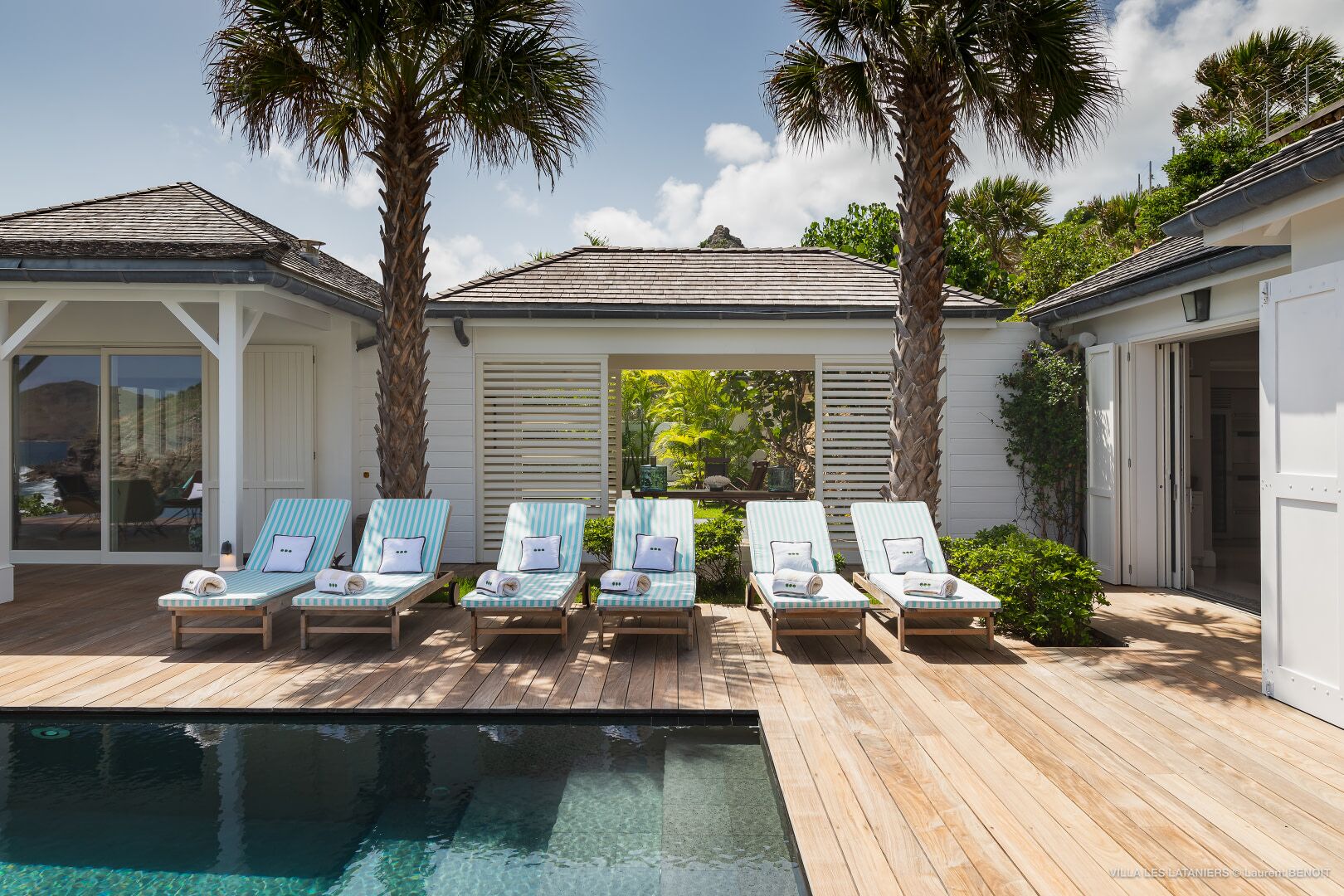 Un espace aménagé au bord de la piscine, avec des chaises longues et une terrasse en bois.