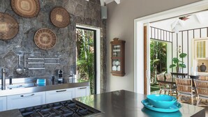 Una cocina moderna con una isla grande, salpicadero de piedra y un área de comedor con sillas de mimbre.