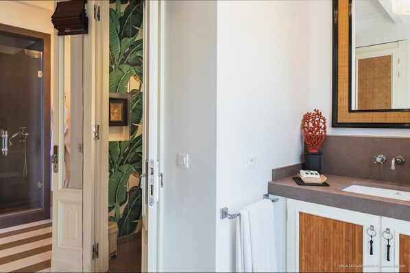 A bathroom with a wooden vanity, a large mirror, and a shower area with a glass door.