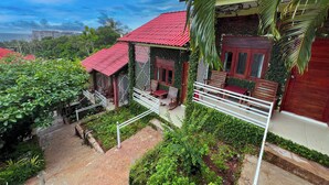 A house with a red roof, surrounded by lush greenery and a clear blue sky. - CALI HILL RESORT & SPA (Phu Quoc)