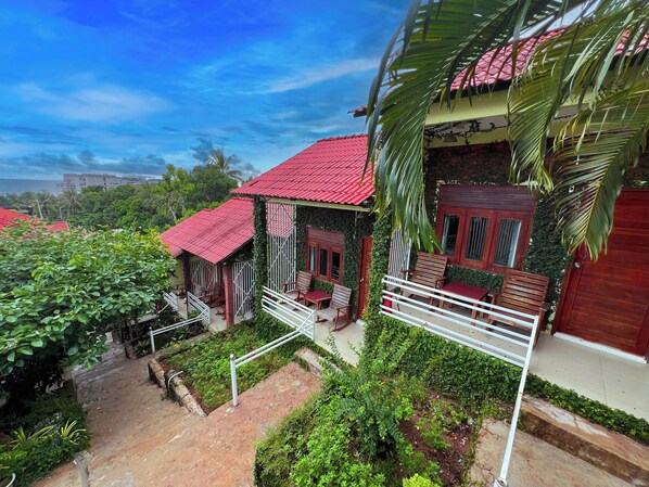 A house with a red roof, surrounded by lush greenery and a clear blue sky.