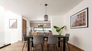 A modern dining area with a wooden floor, a central table with chairs, and a kitchen in the background. - w* | Inspiring 3BR Duplex with Terrace in Polanco (Ciudad de México)