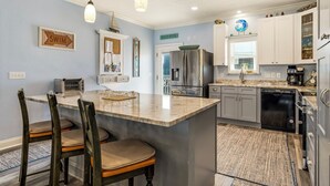 A kitchen with a central island, a refrigerator, a coffee maker, and a dishwasher. - Blue Sky Breeze - Gulf Front, Pet Friendly on the beach (Dauphin Island)