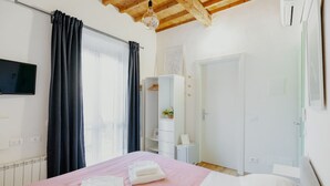 Una camera da letto con un letto, un armadio, una televisione e una finestra con tende.