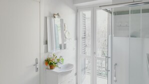 Un bagno moderno con lavandino bianco, specchio e doccia a parete aperta.