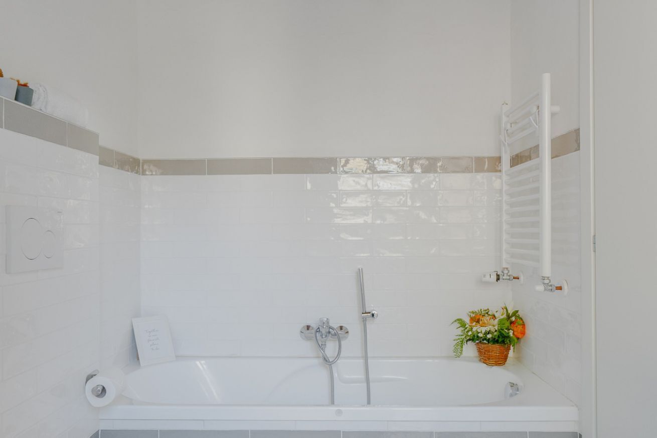 Une salle de bain moderne avec une baignoire blanche, une pomme de douche et un porte-serviettes.