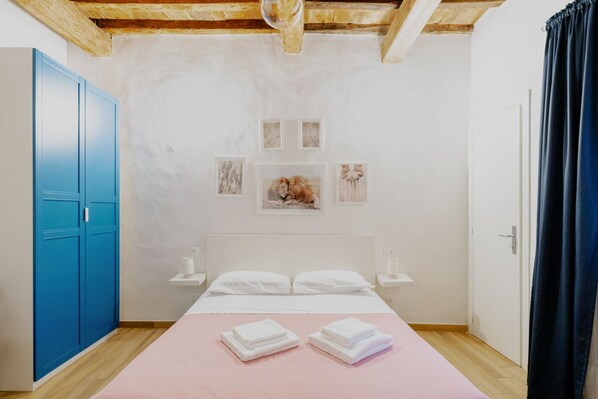 A bedroom with a bed, a blue wardrobe, a white nightstand, and a door. - Double Room with Sofa Bed and Private Bathroom (Firenze)