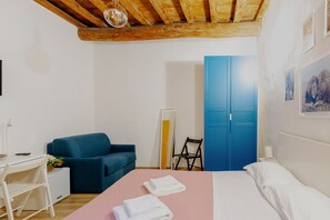 A bedroom with a bed, a desk, a chair, a wardrobe, and a wall with a picture. - Double Room with Sofa Bed and Private Bathroom (Firenze)