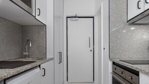 A modern kitchen with white cabinetry, granite countertops, a stainless steel sink, and a built-in oven. - Stylish Living at The Flamingo! (Cape Town)