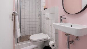 A bathroom with a shower, toilet, sink, and a mirror. - Stylish Living at The Flamingo! (Cape Town)