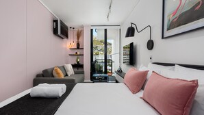A modern hotel room with a large bed, a sofa, a desk, and a TV. - Stylish Living at The Flamingo! (Cape Town)