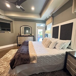 Une chambre à coucher comprenant un lit, une commode, un miroir et un ventilateur de plafond.