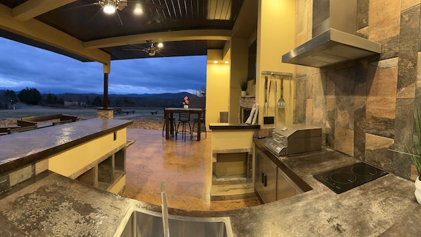 A modern kitchen with a stone backsplash, a built-in oven, and a dining area with a view of the outdoors. - 50% OFF - No Stairs (Sevierville)