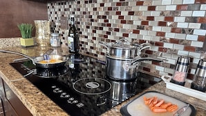 A kitchen with a black induction cooktop, a stainless steel pot, and a cutting board with carrots. - 50% OFF - No Stairs (Sevierville)