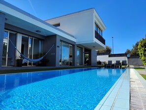 A modern house with a swimming pool, large windows, and a hammock. - Villa Boutique La Quinta (CN)