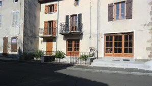 Ein zweistöckiges Gebäude mit Holzh shutters, einem Balkon und einem großen Fenster.
