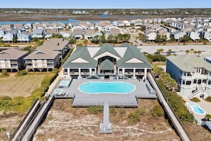 A residential area with a large swimming pool, multiple houses, and a prominent building with a green roof.