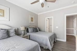 A bedroom with two beds, a ceiling fan, and a walk-in closet.