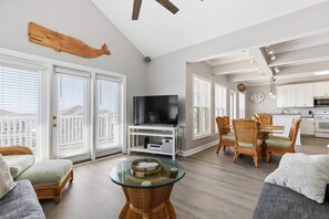 A spacious living room with a television, wicker furniture, and a glass coffee table.