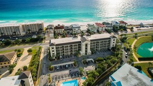 A coastal hotel with multiple buildings, a parking lot, and a view of the ocean. - Fantastic 2-Bed Miramar Condo! Pool & Private Media Room | Fall Specials! (Miramar Beach)