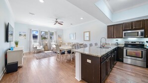 A spacious kitchen with dark wooden cabinets, stainless steel appliances, and a large island. - Fantastic 2-Bed Miramar Condo! Pool & Private Media Room | Fall Specials! (Miramar Beach)