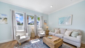 A living room with a light blue wall, a grey sofa, two striped armchairs, a coffee table, and a patterned rug. - Fantastic 2-Bed Miramar Condo! Pool & Private Media Room | Fall Specials! (Miramar Beach)