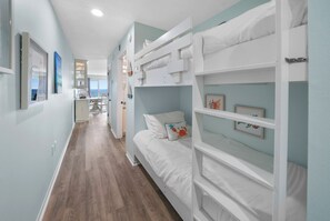Une chambre avec des lits superposés, un coin cuisine et une vue sur la mer.