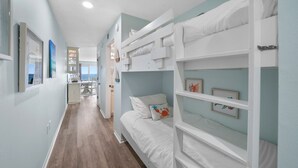 Quarto com beliches, cozinha e vista para o mar.