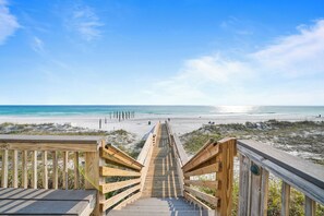 Un escalier en bois mène à une plage d’où l’on a une vue dégagée sur l’océan.
