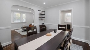 Une salle à manger avec une longue table, des chaises foncées et un mur d’accent de couleur blanche.
