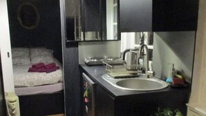 A compact hotel room with a bed, a small kitchenette, a sink, and a mirror. - Nice 2 rooms in the center of town, close to the Garonne river (Toulouse)