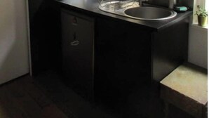 A modern kitchen with a dark countertop, a stainless steel sink, a hanging light fixture, and a window providing natural light. - Nice 2 rooms in the center of town, close to the Garonne river (Toulouse)