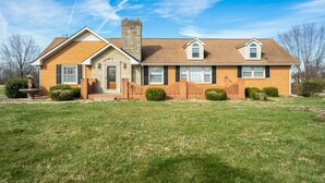 A two-story house with a brick facade, a chimney, and a well-maintained lawn. - Country living at its best, with a beautiful stocked pond to fish in (Springfield)