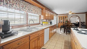 A kitchen with wooden cabinets, a dishwasher, a coffee maker, and a dining area with a table and chairs. - Country living at its best, with a beautiful stocked pond to fish in (Springfield)