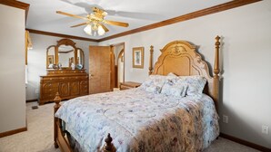 A bedroom with a wooden bed, a ceiling fan, a dresser, and a mirror. - Country living at its best, with a beautiful stocked pond to fish in (Springfield)