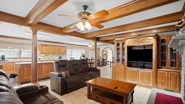 A spacious living room with a ceiling fan, a large wooden entertainment center, and a cozy seating area. - Country living at its best, with a beautiful stocked pond to fish in (Springfield)