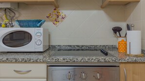 A kitchen with a microwave, stove, and various kitchen utensils.