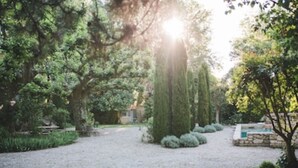 A gravel path in a garden with trees and a stone structure. - Mas Dagan, vacation apartments in Saint Remy to dream away on a romantic estate  (Saint-Rémy-De-Provence)