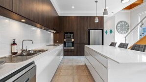 A modern kitchen with white cabinetry, stainless steel appliances, and a central island. - North Entrance Holiday Home (North Entrance)