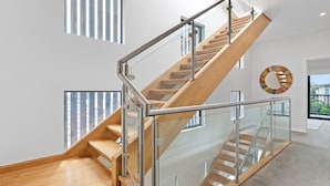 A modern staircase with glass railings and wooden steps, leading to an upper floor. - North Entrance Holiday Home (North Entrance)