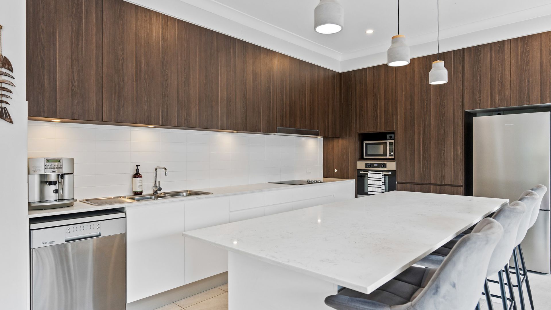 A modern kitchen with a central island, white cabinetry, and a built-in microwave.