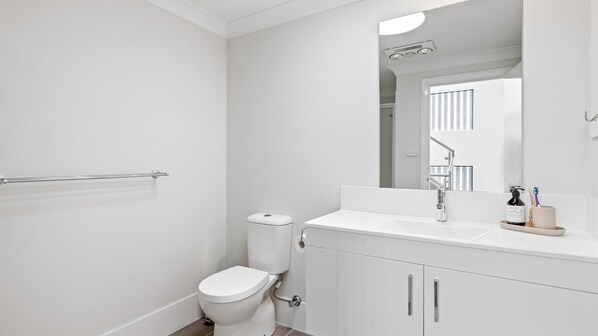 Un baño moderno con inodoro, lavabo y espejo.
