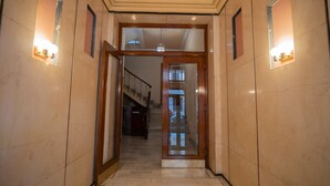 A hallway with a wooden door leading to a staircase. - K23 Color Suites (Athens)