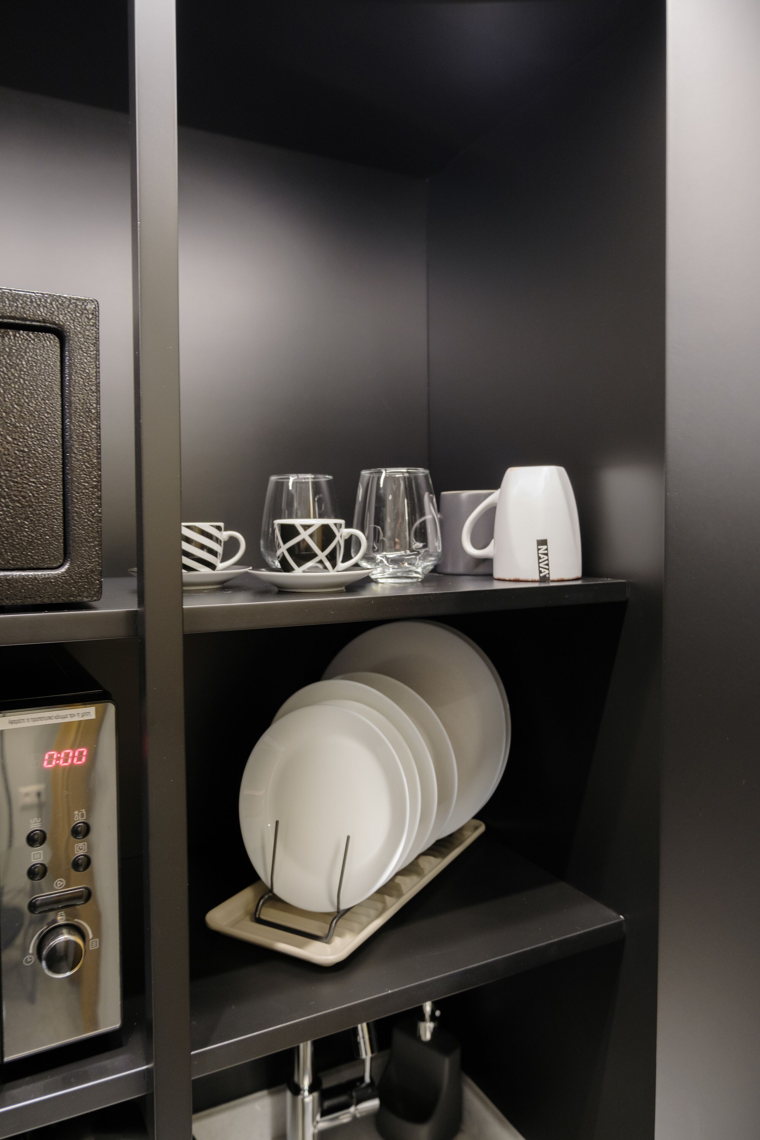 A kitchen area with a microwave, a coffee maker, and a dish rack with plates.