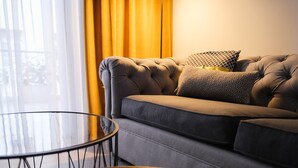 A modern living room with a sofa, a glass coffee table, and a floor lamp. - K23 Color Suites (Athens)