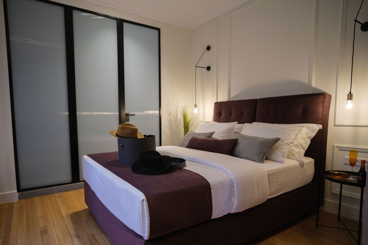 A modern bedroom with a large bed, a bedside table, a wardrobe, and a sliding glass door.