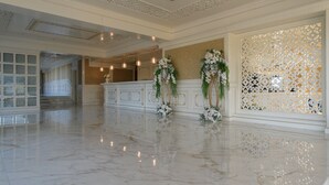 A spacious lobby with a polished marble floor, elegant white decor, and floral arrangements. - Grand Hotel Caraiman (Neptun)