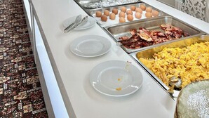 A buffet setup with various food items, including eggs, bacon, and scrambled eggs, arranged on a glass counter. - Grand Hotel Caraiman (Neptun)