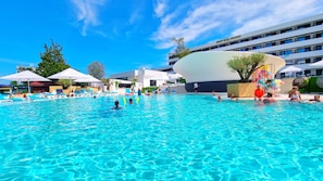 Una amplia piscina al aire libre con agua azul cristalina, rodeada de sillas de descanso y sombrillas.