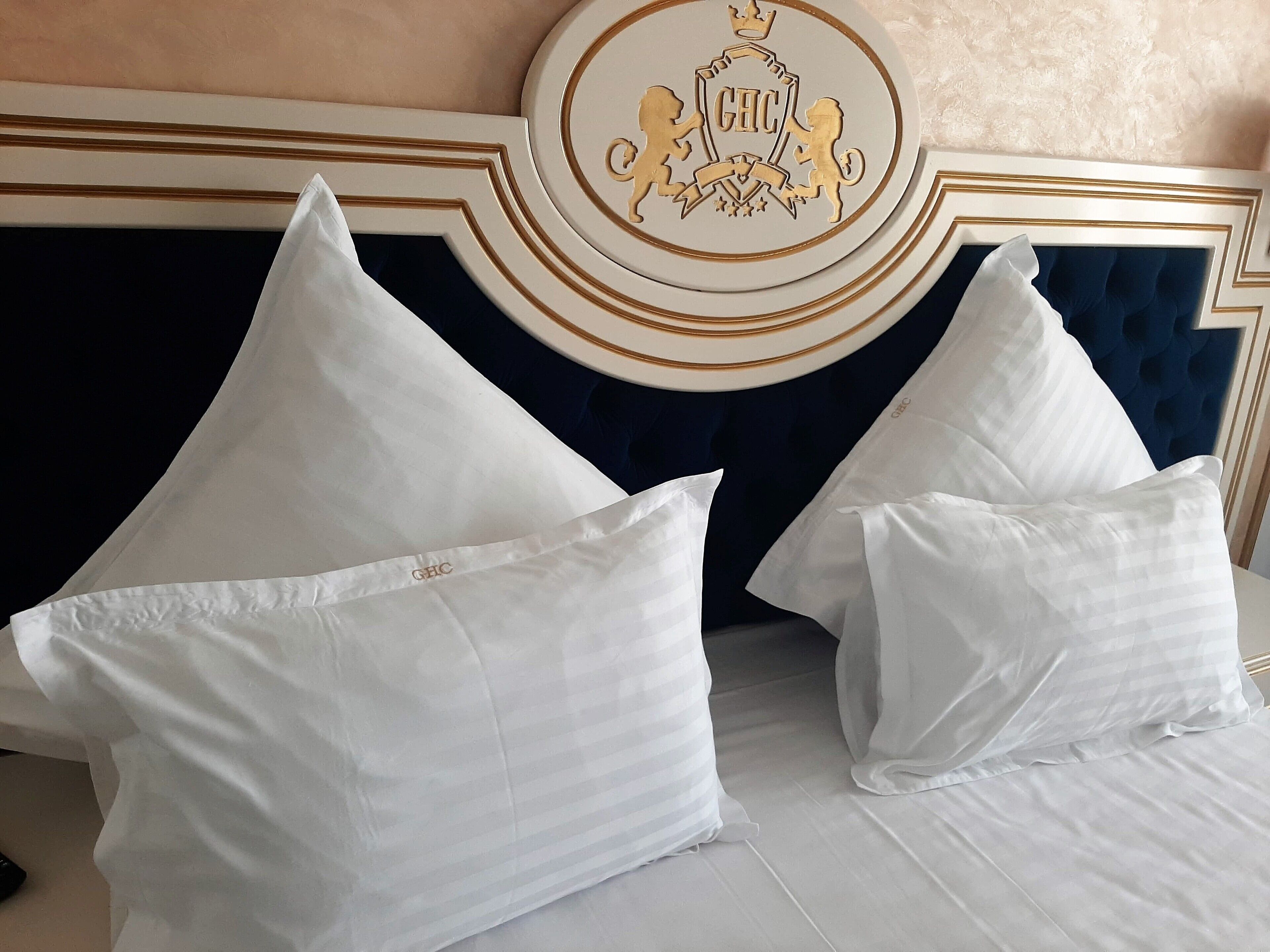 A bed with white pillows and a decorative headboard with a crest.